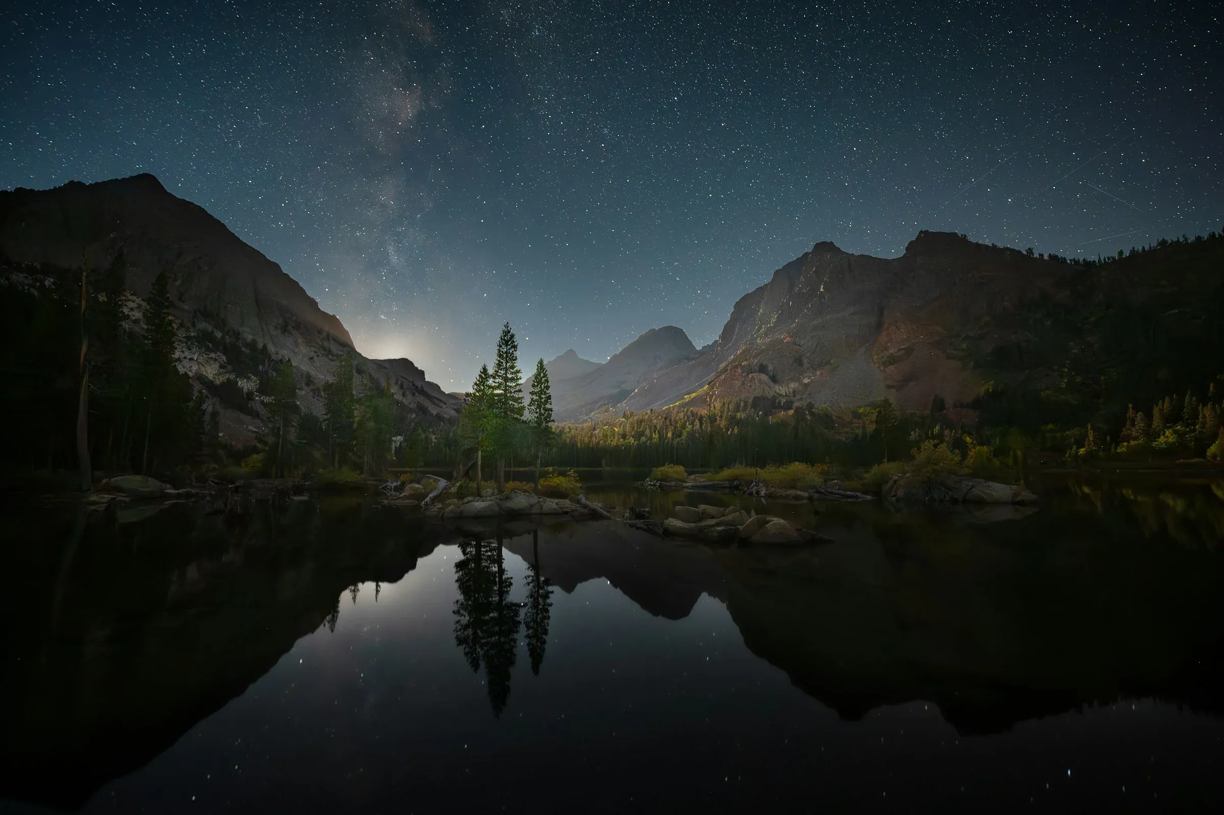 Un lago de montaña de noche, con las estrellas reflejadas en el agua